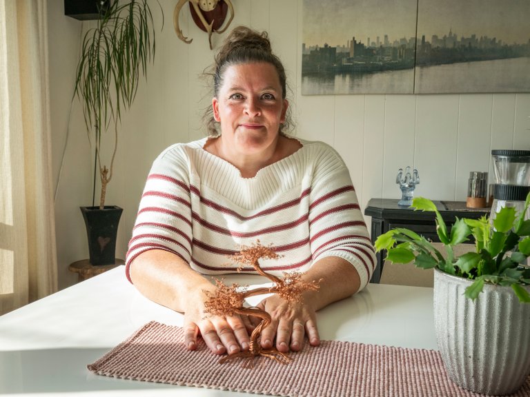 Anette som viser frem et tre hun har laget av kobberledninger