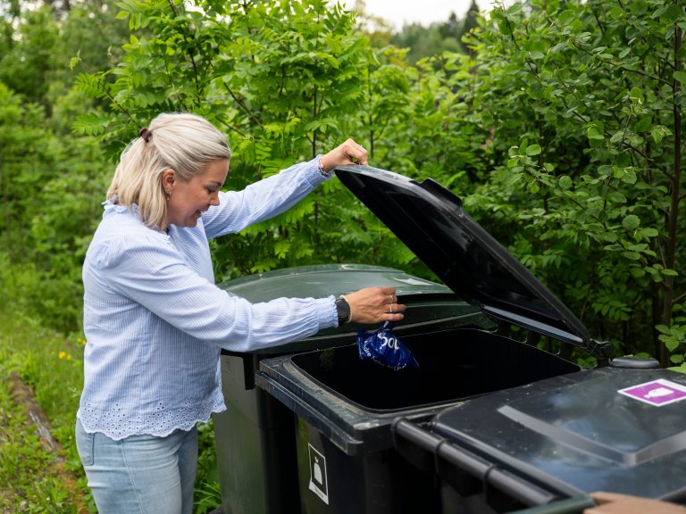 Camilla som kaster en bitteliten pose med restavfall