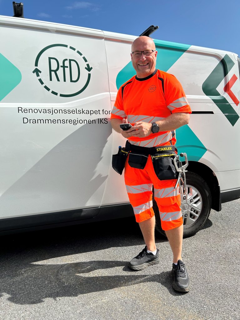 Mann i RfD-uniform står smilende foran en bil med RfD-logo på.