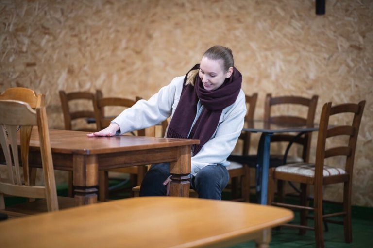 En kvinne sitter ved et møbel på ombrukstorget.